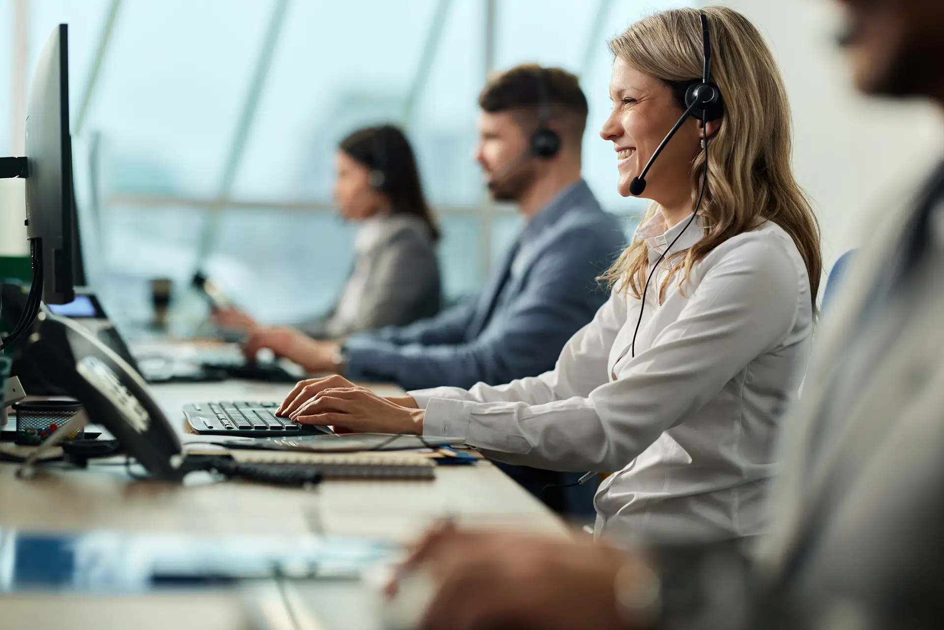 row of people in headsets working at computers