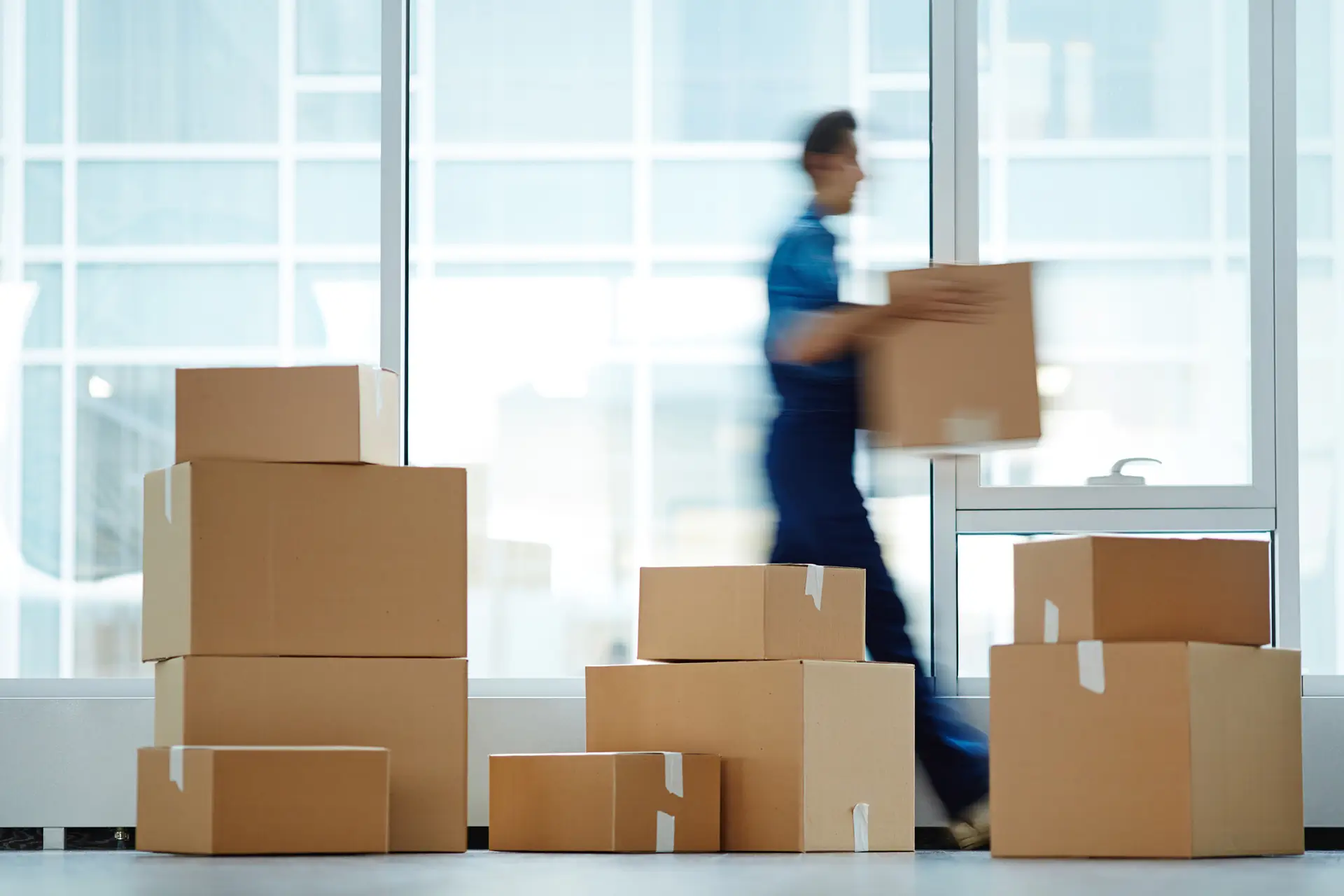 man carrying box with stacked boxes in foreground